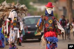 Gule Wamkulu baila miembros de la sociedad secreta con máscaras sangrientas y atuendos coloridos caminando por las calles camino a su actuación de danza ritual en Harare, Zimbabue, el 23 de octubre de 2022.