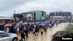 People make their way through a flooded street after heavy rains in Douala, Cameroon, August 12, 2021.