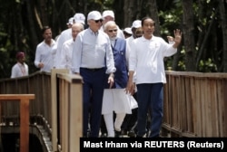 Presiden Joko Widodo memberi isyarat saat Presiden AS Joe Biden Kanselir Jerman Olaf Scholz (belakang kiri), Perdana Menteri India Narendra Modi dan para pemimpin lainnya berjalan bersama saat acara penanaman bakau di Bali. (Foto: via Reuters)