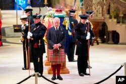 Britain's King Charles III, center, and other members of the royal family hold a vigil at the coffin of Queen Elizabeth II at St Giles' Cathedral, Edinburgh, Scotland, Sept. 12, 2022, as members of the public walk past.