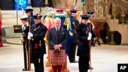 Britain's King Charles III, center, and other members of the royal family hold a vigil at the coffin of Queen Elizabeth II at St. Giles' Cathedral, Edinburgh, Scotland, Sept. 12, 2022, as members of the public walk past.