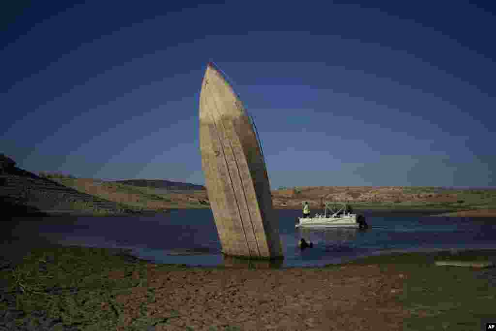 FILE - A formerly sunken boat sits upright into the air with its stern stuck in the mud along the shoreline of Lake Mead at the Lake Mead National Recreation Area, June 10, 2022, near Boulder City, Nev.