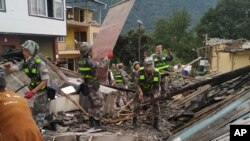 In this photo released by Xinhua News Agency, soldiers clear debris to search for survivors at an earthquake hit Moxi Town of Luding County, southwest China's Sichuan Province, Sept. 6, 2022.
