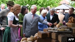 FILE - Britain's Prince Charles, Prince of Wales, center, looks at regional products as he visits the organic farm Herrmannsdorfer Landwerkstaetten in Glonn, southern Germany, on May 10, 2019.