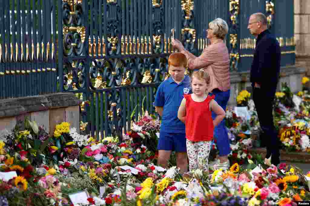 La gente, entre ellos niños, mira los tributos florales y rinde homenaje en el Castillo de Hillsborough, tras la muerte de la Reina Isabel, en Royal Hillsborough, Irlanda del Norte, el 12 de septiembre de 2022.