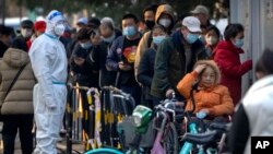 北京居民2022年11月17日冒着刺骨寒风在一个检测站外排长队等候新冠核酸检测。