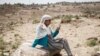 FILE - A woman attempts to get a mobile phone signal after most of an area was in blackout, in Samre, southwest of Mekele in Tigray region, Ethiopia, on June 20, 2021.