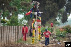 Gule Wamkulu baila miembros de la sociedad secreta con máscaras sangrientas y atuendos coloridos caminando por las calles camino a su actuación de danza ritual en Harare, Zimbabue, el 23 de octubre de 2022.