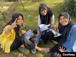 Ida Rosiyatun (kanan) dan dua remaja puteri duduk di rumput, memegang buku dan tersenyum ke kamera. (Courtesy: Ilsa Diasty)