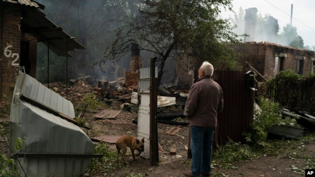 Oleksander Zaitsev, 67, stands in front of the house where his friend was found dead after a Russian attack in Pokrovsk region, Ukraine, Sunday, Sept. 11, 2022. (AP Photo/Leo Correa)