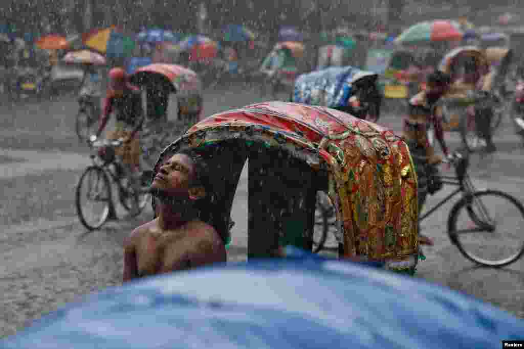 A rickshaw puller enjoys rain during monsoon in Dhaka, Bangladesh.