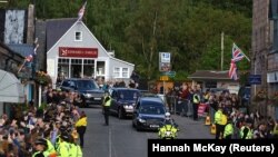 Les gens s'alignent dans la rue alors que le corbillard transportant le cercueil de la reine Elizabeth de Grande-Bretagne traverse le village de Ballater, près de Balmoral, en Écosse, en Grande-Bretagne, le 11 septembre 2022.