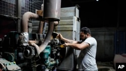 FILE - Aqeel Abdullah prepares an electricity generator to power private homes in Baghdad, Iraq, July 12, 2022.