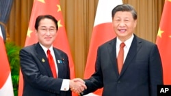 Perdana Menteri Jepang Fumio Kishida (kiri), dan Presiden China Xi Jinping berjabat tangan di sela-sela forum Kerja Sama Ekonomi Asia-Pasifik di Bangkok, , 17 November 2022. (Kyodo via AP)