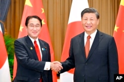 Perdana Menteri Jepang Fumio Kishida, kiri, dan Presiden China Xi Jinping berjabat tangan saat pertemuan mereka di sela-sela forum Kerja Sama Ekonomi Asia-Pasifik, 17 November 2022, di Bangkok. (Foto: Kyodo melalui AP)