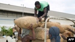 FILE - Workers remove bags of cashew nuts from a truck outside the Fludor plant in Zogbodomey, Benin, on March 29, 2019. Benin is one of Africa's main cashew producers and a new industrial zone there is processing cashews locally instead of exporting them for processing.