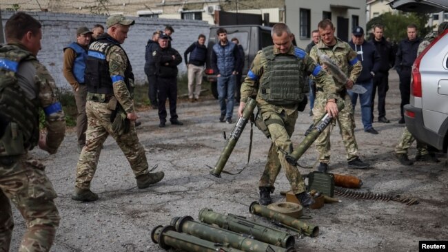 A police sapper sorts unexploded mine shells and weapons after return from the village of Udy, recently liberated by Ukrainian Armed Forces, in the town of Zolochiv, Kharkiv region, Ukraine September 12, 2022. (REUTERS/Gleb Garanich)