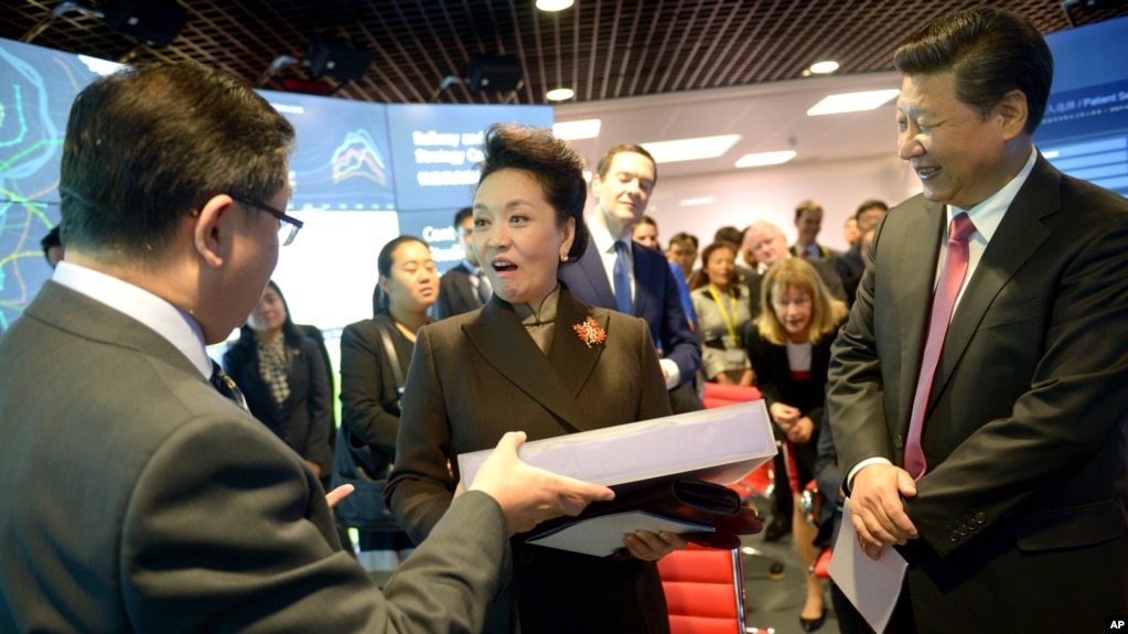 2015年10月21日，中国国家主席习近平夫妇访问伦敦帝国理工学院期间，中国第一夫人彭丽媛在接受赠送的礼物。（美联社照片）(photo:VOA)