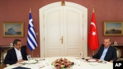 FILE - In this photo provided by the Turkish Presidency, Greek Prime Minister Kyriakos Mitsotakis, left, is seen with Turkish President Recep Tayyip Erdogan during their meeting in Istanbul, Turkey,March 13, 2022. 