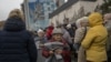 Local residents hold blankets and lamps during an aid supply distribution in the center of Kherson, Ukraine, on Nov. 17, 2022. 