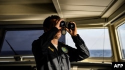FILE - A Greek coast guard member looks through his binoculars as he patrols with his colleagues on the Mediterranean sea between the Greek island of Lesbos and Turkey, March 19, 2019. 