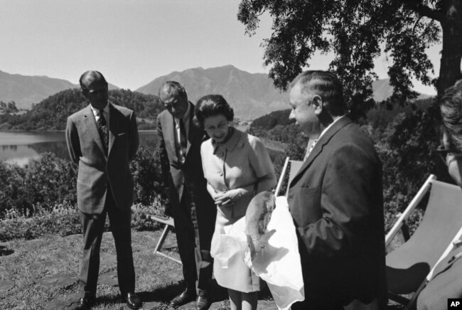 Durante la estancia de la reina Isabel II y el príncipe Felipe en un hotel a la orilla del lago Pucón en el sur de Chile, el anfitrión ofrece a la reina un salmón de 13 libras, patrimonio culinario de la región, imagen captada el 15 de noviembre de 1968.