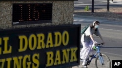 A bicyclist passes a bank sign displaying a temperature of 116 degree in Sacramento, Calif., Sept. 5, 2022. 