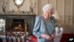 FILE - Britain's Queen Elizabeth II smiles while receiving the President of Switzerland Ignazio Cassis and his wife Paola Cassis during an audience at Windsor Castle in Windsor, England, Thursday, April 28, 2022.