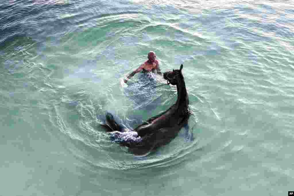 Denis Hooker trains his race horse named Pereque in the sea near the shore of San Andres Island in Colombia.