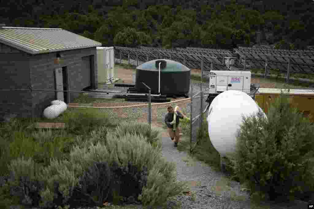 Garnett Querta carries a hose as he fills his water truck on the Hualapai reservation, Aug. 15, 2022, near Peach Springs, Ariz.&nbsp;&nbsp;
