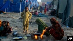 Survivors of heavy flooding from monsoon rains take refuge as they prepare tea at a makeshift tent camp set up by the U.N. Refugee Agency UNHCR, in Sukkur, Pakistan, Sept. 10, 2022. 