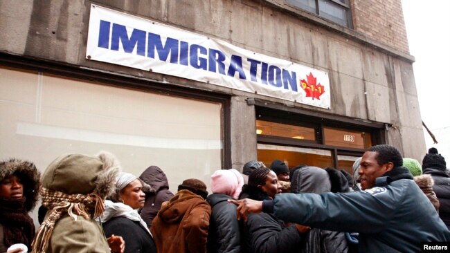 FILE - A security guard instructs members of Canada's Haitian community as they stand in line at an immigration consulting office in Montreal in January 2010.