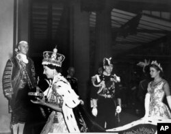 FILE - Ratu Inggris Elizabeth II, membawa bola dan tongkat kerajaan, memasuki Istana Buckingham setelah upacara penobatannya di Westminster Abbey London, 2 Juni 1953. (AP Photo/Pool via AP, File)