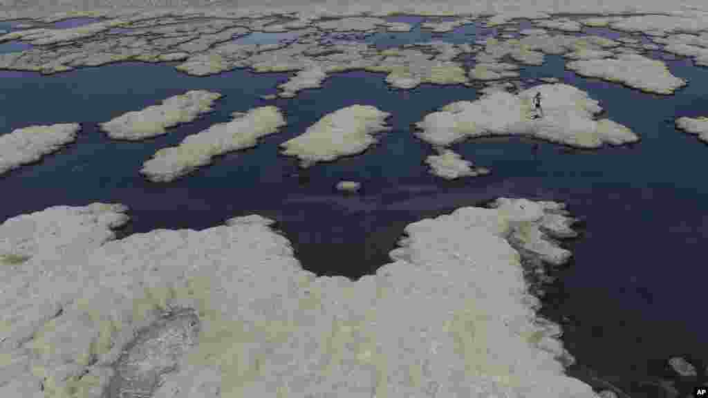 Olof Wood walks across reef-like structures called microbialites, exposed by receding waters at the Great Salt Lake, Sept. 6, 2022, near Salt Lake City. (AP Photo/Rick Bowmer)