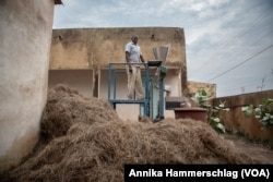 Keba Barry, fonio processing manager at GIE Koba Club, stands atop a fonio processing machine in Kedougou, Senegal, Nov. 15, 2022. (Annika Hammerschlag/VOA)