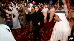 FILE - Sheikha Moza bint Nasser al-Missned, wife of Qatari Emir Sheikh Hamad bin Khalifa al-Thani, waves to the crowds as she arrives Doha, Dec. 3, 2010, returning from Zurich following the official announcement that Qatar will host the 2022 Soccer World Cup.