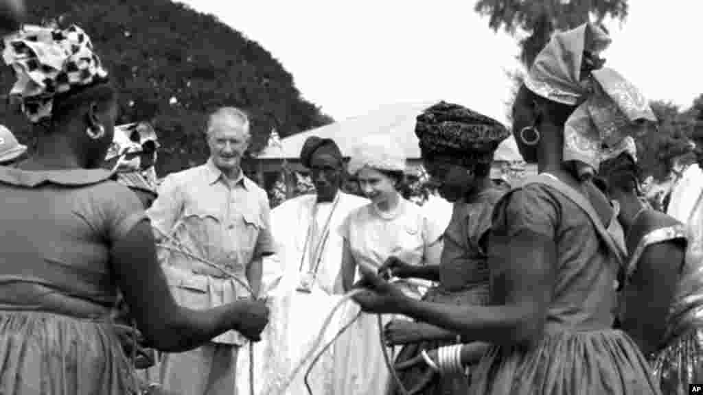 Britain&#39;s Queen Elizabeth II, centre, looks on as local women draw water in a market place at Jowara, Gambia, on Dec. 5, 1961. Queen Elizabeth is on a three-day visit to Gambia, Britain&#39;s oldest African colony. It was the last port of call in the Royal tour of West Africa. (AP Photo/Leslie Priest)
