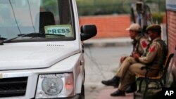 FILE - Indian policemen rest on a bench at the entrance of Press Enclave, which houses several newspaper offices, in Srinagar, Indian-controlled Kashmir, Sept. 8, 2021. 