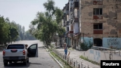 FILE - A Ukrainian police officer urges a resident to leave Toretsk before fierce fighting erupts. Russian troops said they have captured the village of Urozhayne in the Donestsk region.