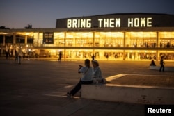Ljudi razgovaraju ispred natpisa "Vratite ih kući", koji se odnosi na taoce kidnapovane tokom smrtonosnog napada palestinske islamističke grupe Hamas 7. oktobra, u Tel Avivu, Izrael, 2. juna 2024.