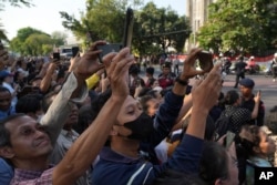 Worshipers hold handphone as they wait for Pope Francis past outside the Cathedral of Our Lady of the Assumption, in Jakarta, Indonesia, Sept. 4, 2024.