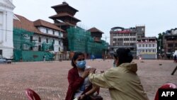 A health worker inoculates a woman with the COVID-19 vaccine in Kathmandu on May 25, 2021. 