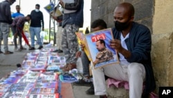 FILE - Ethiopians read newspapers and magazines reporting on the military confrontation in the country, one of which shows a photograph of Prime Minister Abiy Ahmed, on a street in the capital Addis Ababa, Ethiopia, on Nov. 7, 2020.