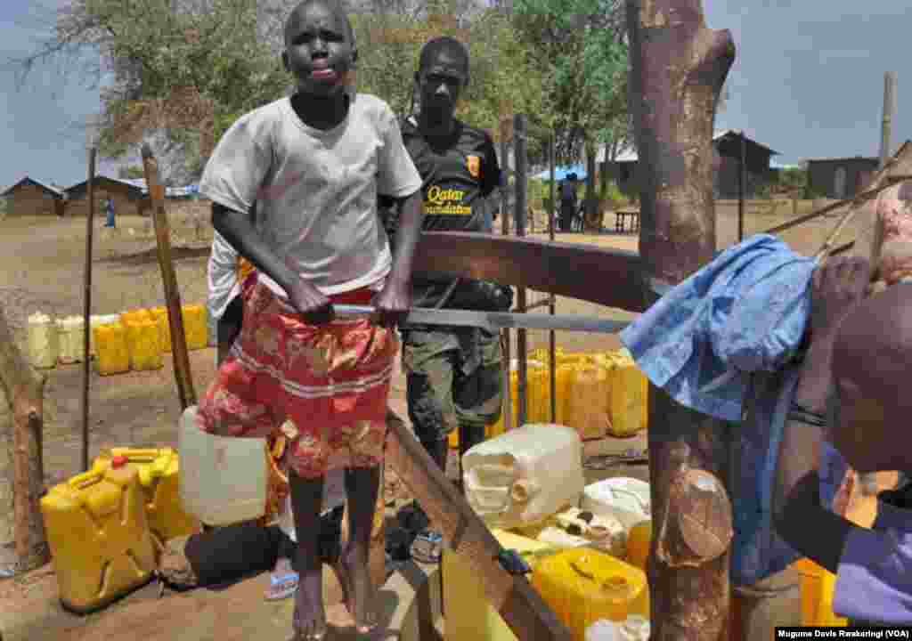 Msichana wa Sudan Kusini akiruka juu na chini kusukuma maji kutoka kisima ya maji huko Gudere, karibu na Juba. Jumuia ya Kimataifa inapeleka fedha Sudan Kusini kujaribu kujenga miundo mbinu ya huduma ya maji. (VOA/Mugume Davis Rwakaringi)