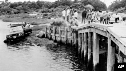 FILE - In this July 19, 1969 file photograph, crowds watch as U.S. Sen. Edward Kennedy's car is pulled from water at the Dyke Bridge in Edgartown, Mass.