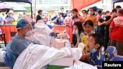 A medical worker collects a swab from a resident during a mass testing for the coronavirus disease (COVID-19) at a makeshift testing site at a stadium in Guangzhou, Guangdong province, China May 30, 2021.