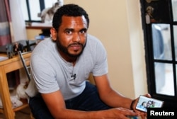 Andom Gebreyesus, 39, who was an Ethiopian electrical engineer in Tigray before fleeing when the conflict started in the Tigray region, shows his family photograph on his mobile phone during a Reuters interview in Nairobi, Kenya, Nov. 3, 2022.