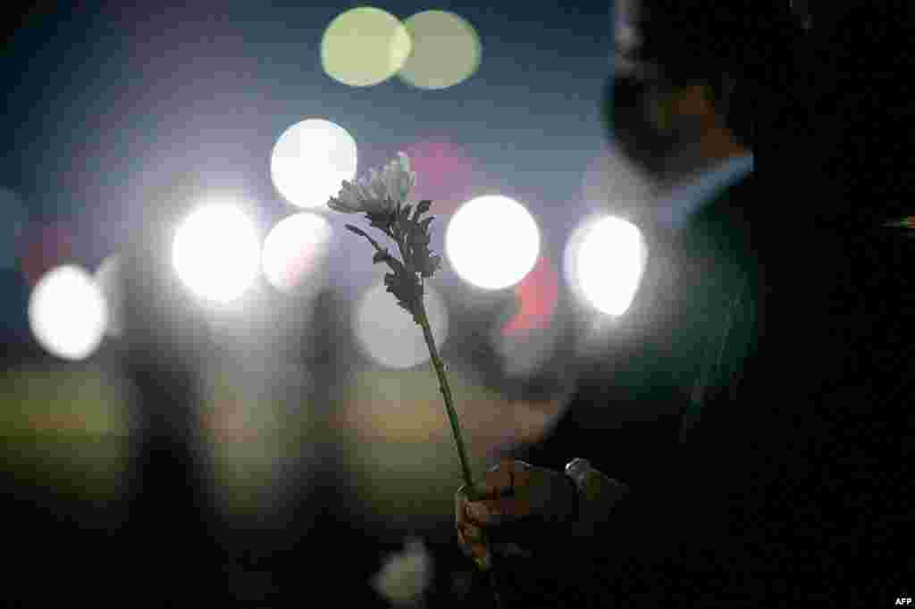 A man holds a white chrysanthemum as he prepares to pay tribute in front of a joint memorial altar for victims of the deadly Halloween crowd surge, outside the city hall in Seoul on November 1, 2022.