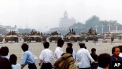FILE - Residents gather to look at the military hardware in Tiananmen Square, Beijing, June 7, 1989, after soldiers and tanks had cleared the square of striking students.