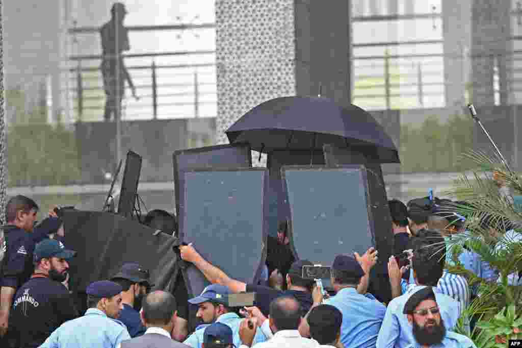 Security workers with ballistic shields escort former Pakistani Prime Minister Imran Khan, at the High Court in Islamabad.